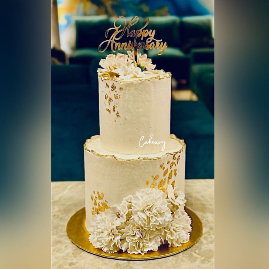 Two-tier ivory anniversary cake with gold leaf
